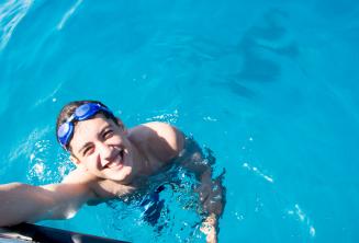 Comino'da teknenin yanında yüzen bir öğrenci